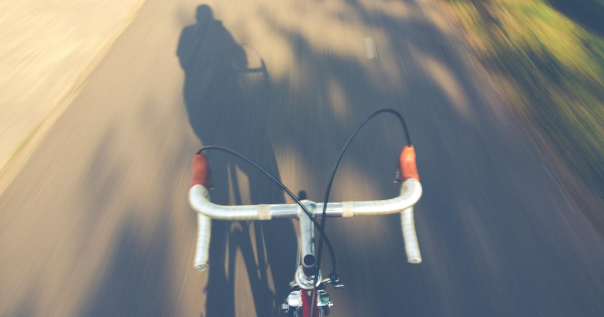 Cyclist riding along Corfu coastal road with sea view