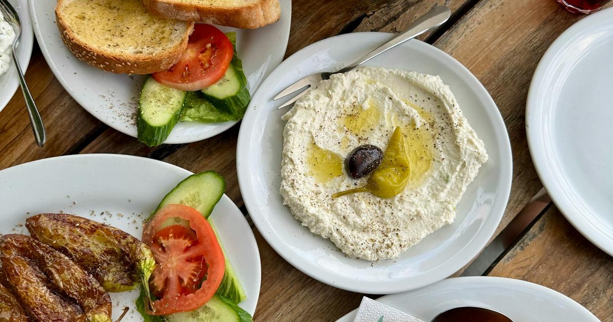 Plates of traditional Corfu food served at a local taverna with wine and bread