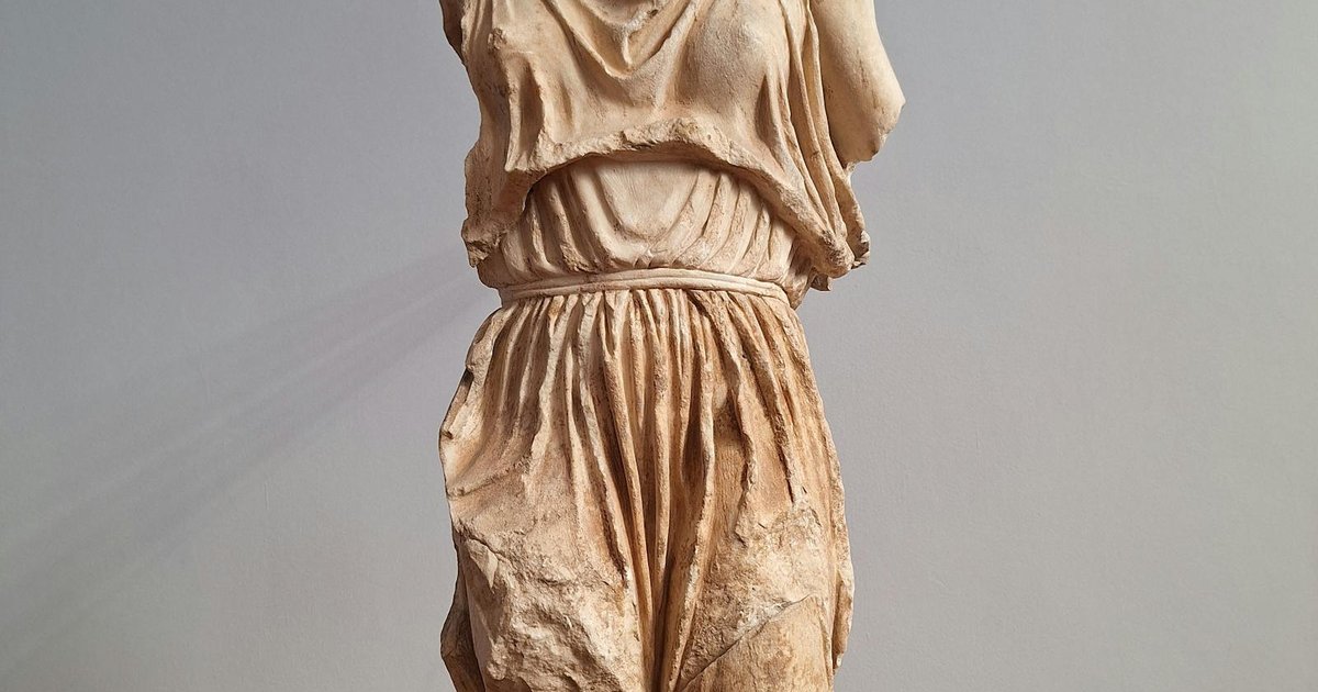 Visitor walking past classical exhibits at the Archaeological Museum of Corfu